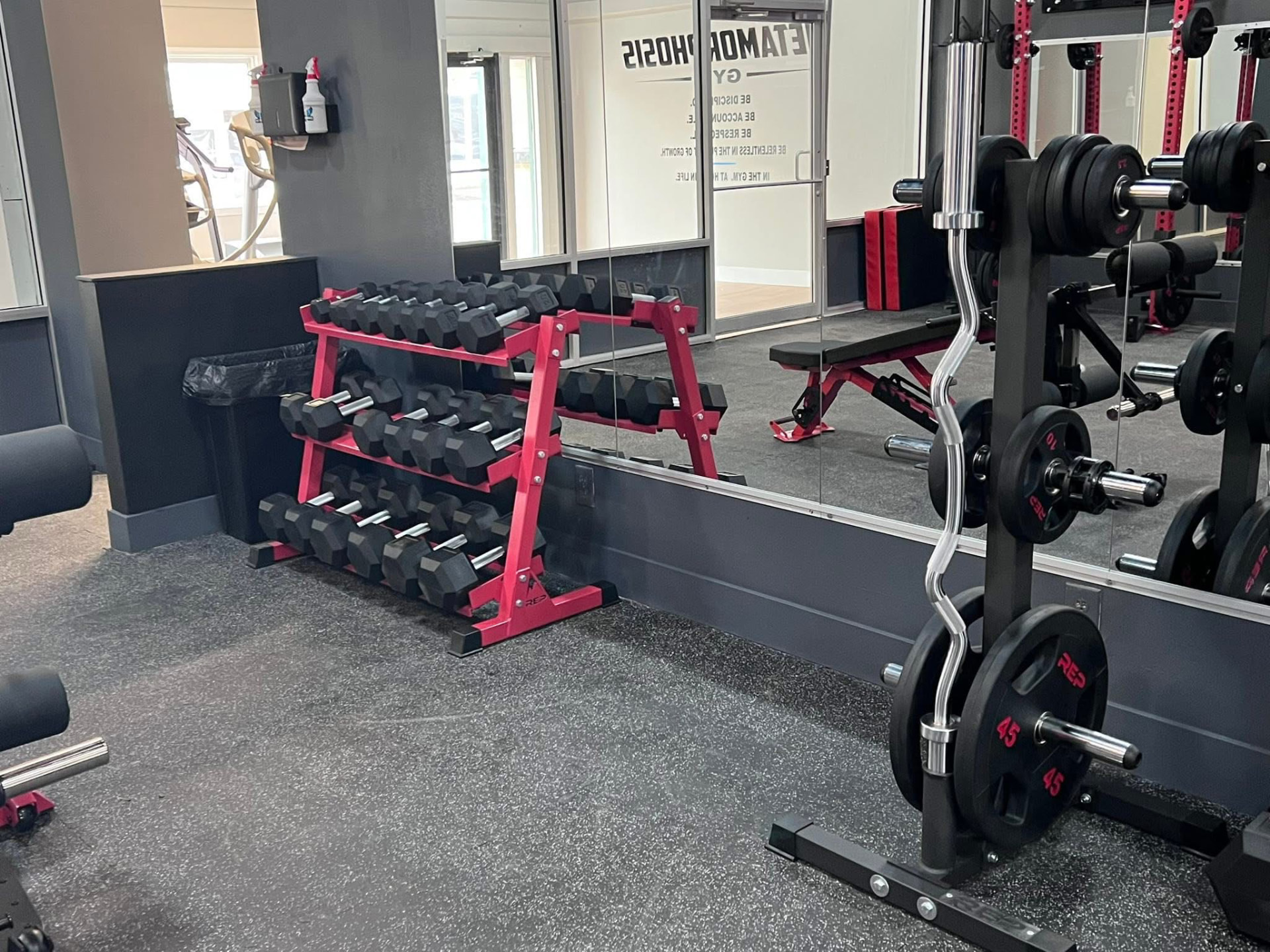 Dumbbell rack and curl bar near the gym entrance